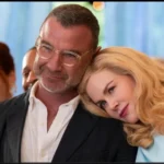 Liev Schreiber smiling with a woman leaning on his shoulder during a public event.